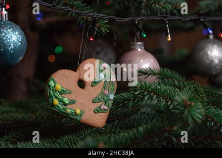 Christmas decorations hung on a natural spruce tree. Christmas balls, hand-decorated gingerbreads and chains on the Christmas tree. Stock Photo
