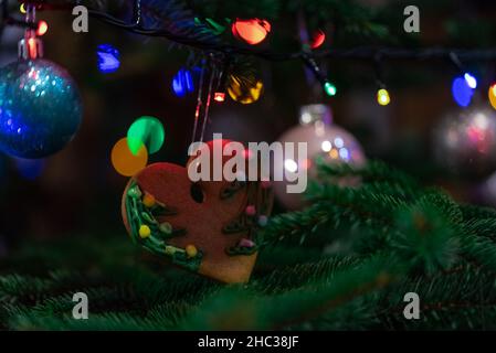 Christmas decorations hung on a natural spruce tree. Christmas balls, hand-decorated gingerbreads and chains on the Christmas tree. Stock Photo