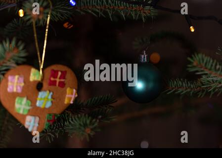 Christmas decorations hung on a natural spruce tree. Christmas balls, hand-decorated gingerbreads and chains on the Christmas tree. Stock Photo