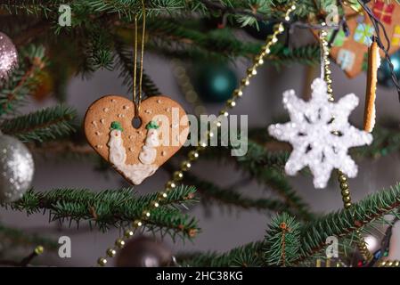 Christmas decorations hung on a natural spruce tree. Christmas balls, hand-decorated gingerbreads and chains on the Christmas tree. Stock Photo