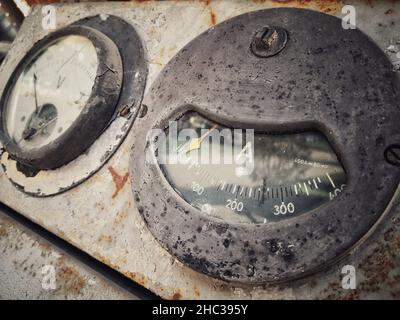 Vintage ancient amperemeter scale, on a rusty abandoned industrial interface. Stock Photo