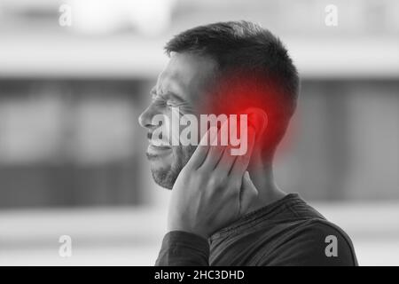 Young man suffering from of strong earache or ear pain. Ear diseases Stock Photo