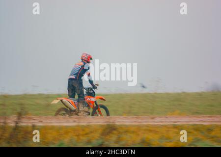 a motor cyclist (biker) riding his off-road motorbike along a muddy stone track on Salisbury Plain, Wiltshire Stock Photo