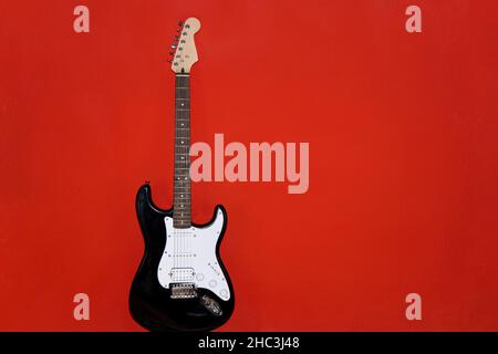 Isolated black and white electric guitar on red background Stock Photo