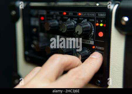 Close up of a man's hand switching on an amplifier. Stock Photo