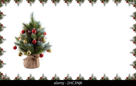 Green pine branches decorated with golden, silver, red balls form a frame with a decorated Christmas tree, copy space in the middle. Isolated on white Stock Photo