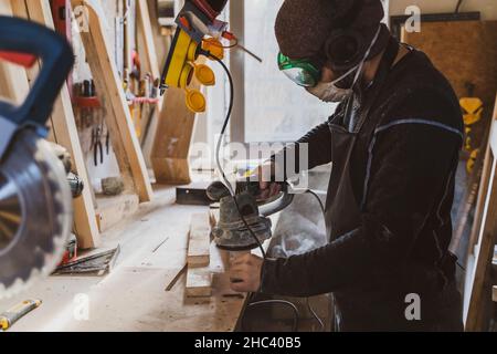 Man working with wood in workshop using sanding machine. Stock Photo