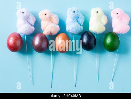 top view of colorful Easter eggs and festive decorations - toys bunny on a stick. blue background Stock Photo