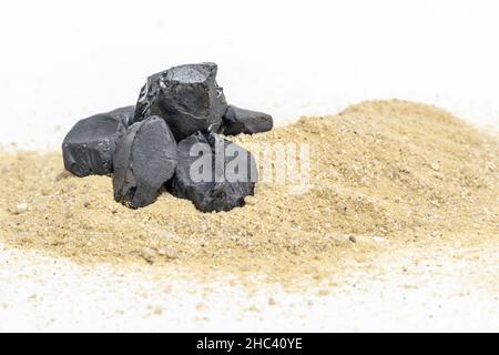 Black stones in brown sand pile isolated on white background. With clipping path on rock Stock Photo