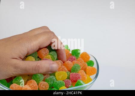Gummy Candies. Man taking a handful of jelly candies isolated on white background. Stock Photo