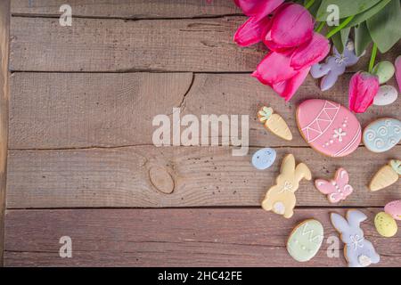 Easter gingerbread cookies, spring flowers and eggs on wooden background. Cozy home Easter greeeting card concept, copy space top view Stock Photo