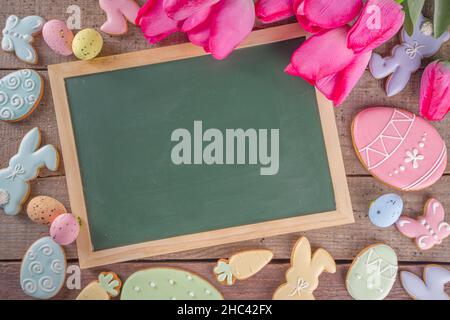Easter gingerbread cookies, spring flowers and eggs on wooden background. Cozy home Easter greeeting card concept, copy space top view Stock Photo