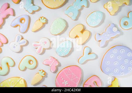Easter cookie layout. Sweet pastel colored Easter sugar glazed cookies, letters, bunny rabbits, eggs, other symbols. Dark shadows trendy pattern top v Stock Photo