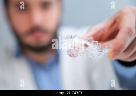 Unrecognizable orthodontist holding invisible dental aligners. Stock Photo