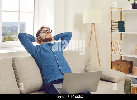 Happy man relax on sofa distracted from computer work Stock Photo