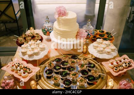 Wedding table set with bunk cake, pastries, macaroons, desserts and sweets Stock Photo