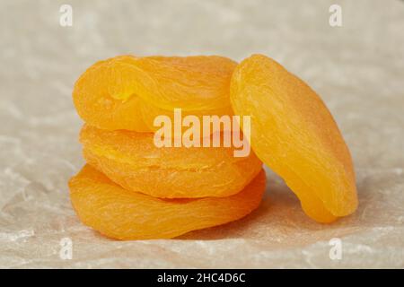 Dried apricots lie on crumpled paper in a stack, close-up photo Stock Photo