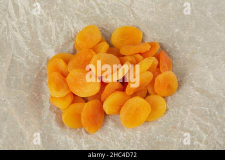 A handful of dried apricots lie on crumpled light paper Stock Photo