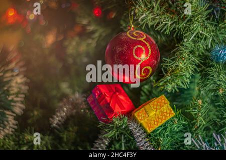 Festive decorations against background of green New Year tree: balls, garland, tinsel and gift boxes Stock Photo
