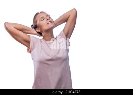 A relaxed adult woman standing with her hands behind head Stock Photo