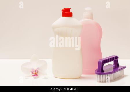 Bottles of dishwashing liquid and brush on white background. Stock Photo