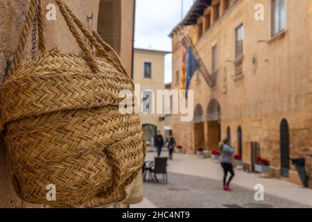 Close-up of a wicker basket of Majorcan handicraft called Senalla. In the background, out of focus, the Town Hall square of the Majorcan town of Campo Stock Photo