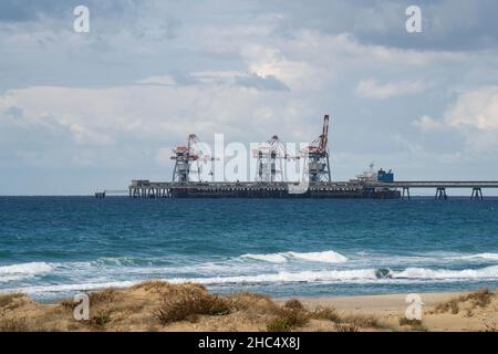 Hadera, Israel - December 16th, 2021: A cargo ship unloading coal at the wharf of the 'Orot Rabin' power station off the mediterranean beach near Hade Stock Photo