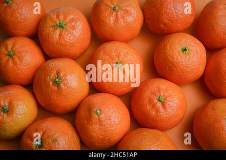 group of organic tangerines in disorder on an orange paper background Stock Photo