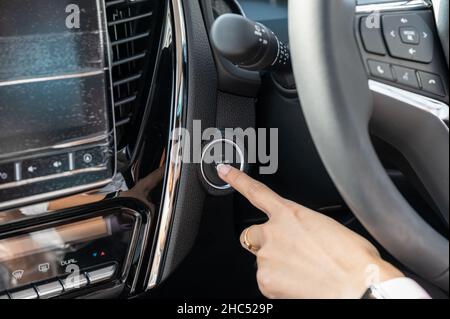Female finger pushing on engine start botton in modern car Stock Photo