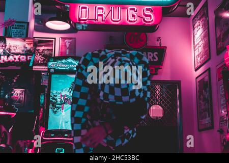 Closeup of the person in a checkered hoodie against the aesthetic gaming room. Stock Photo