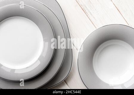 White round classical porcelain plates with a gray pattern stand on a white table Stock Photo