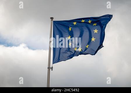 Flag of the European Union waving in the wind on flagpole in slow motion on cloudy sky background Stock Photo