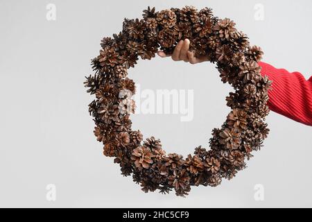 Christmas wreath of natural pine cones in woman hands. Concept eco friendly Xmas holiday. DIY. Stock Photo
