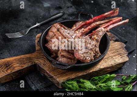 BBq Grilled lamb mutton chops steaks in a pan. Black background. Top view Stock Photo