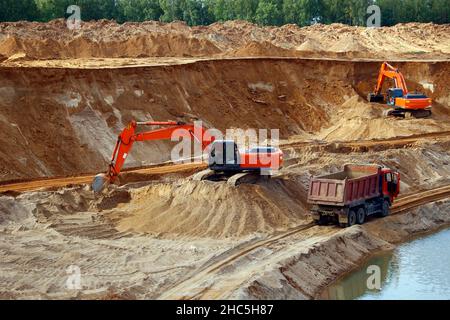 Loading sand into trucks on the sandy career, Mining. Excavators and trucks Stock Photo