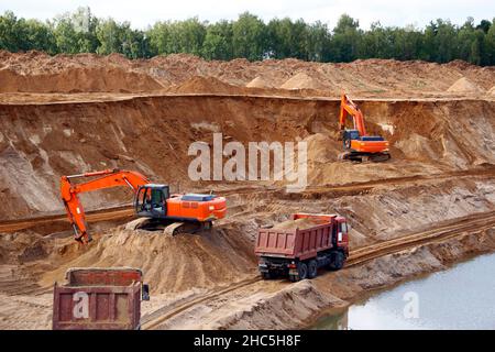 Loading sand into trucks on the sandy career, Mining. Excavators and trucks Stock Photo