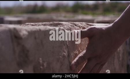Man's hand touching wall outdoor - concept of native place. Close up of man touching wall - concept of memories about the place. Young man hand touchi Stock Photo