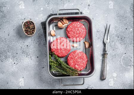 Fresh Raw Ground mince beef meat Hamburger steak patty in a steel tray. Gray background. Top view Stock Photo