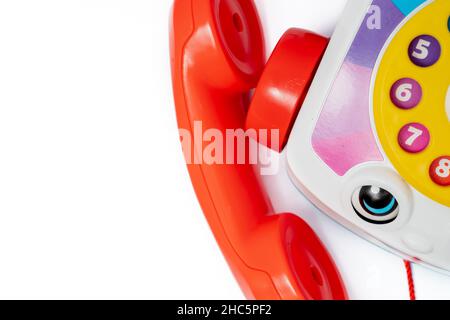 Children's toy landline phone with a red receiver, a dial and a smile on the body isolated on white Stock Photo