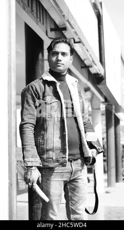 A vertical shot of a South Asian man posing in grayscale Stock Photo