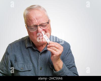 Man swabbing nostril with COVID-19 home antigen test kit. Stock Photo