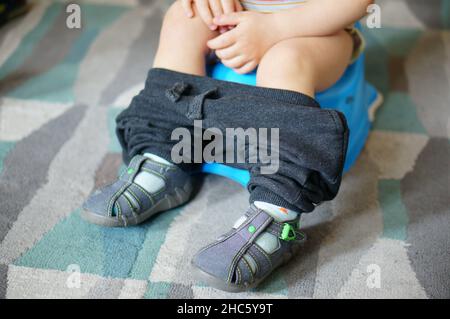 Young boy sitting on a potty put on a carpeted floor Stock Photo