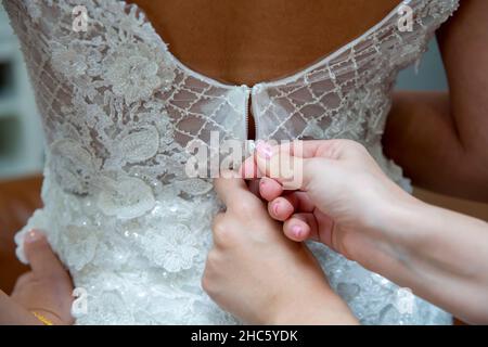 bridesmaid tying bow on wedding dress, close up Stock Photo