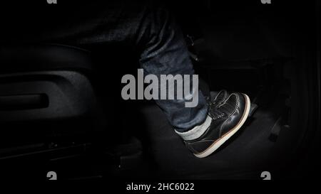 Accelerator and breaking pedal in a car. Close up the foot pressing foot pedal of a car to drive ahead. Driver driving the car by pushing accelerator Stock Photo