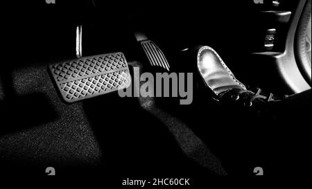 Accelerator and breaking pedal in a car. Close up the foot pressing foot pedal of a car to drive ahead. Driver driving the car by pushing accelerator Stock Photo