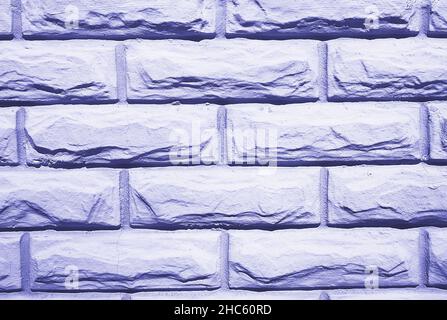Background from wall of bricks stacked in row tinted in trendy color of 2022 by very peri Stock Photo