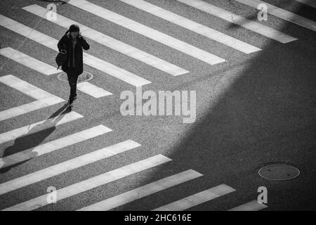 A woman with a large bag stands right at the corner where 2 zebra crossings meet in this photo from a tall building, Weining Road, Shanghai, China Stock Photo