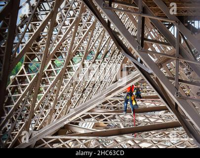 Trabajos de mantenimiento por dos operarios en la estructura metálica de la torre Eiffel en Paris, Francia Stock Photo