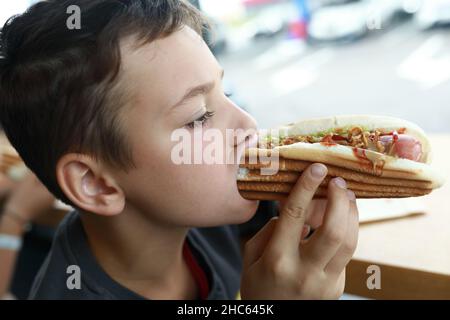 Portrait of boy eating Hot Dog in restaurant Stock Photo