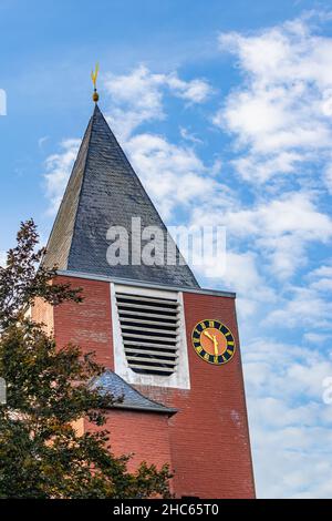 Vertical shot of a red bricked building with a dark grey bricked pyramid and a small clock on it Stock Photo